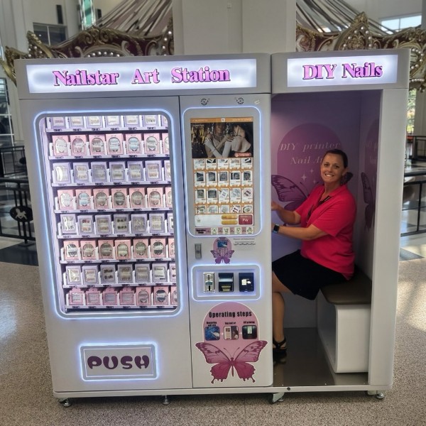 A stocked lavender Nailstar Art Station with a woman seated in the DIY nail booth.